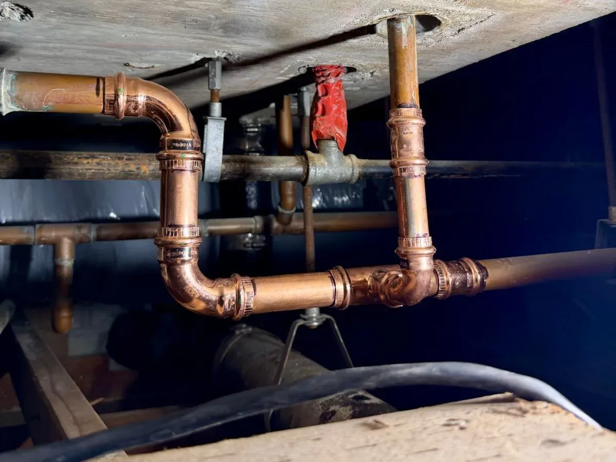 New copper water lines run under a floor, joined with press fittings