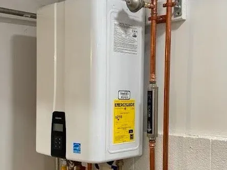 A wall-mounted tankless water heater plumbed in with copper supply lines and isolation valves